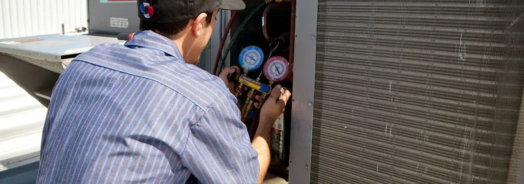HVAC technician servicing a condenser unit in Struthers